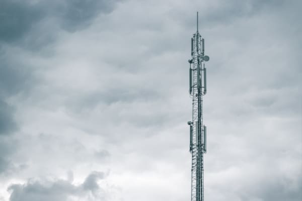 Funkmast mit dunklen Wolken im Hintergrund; Telekommunikation