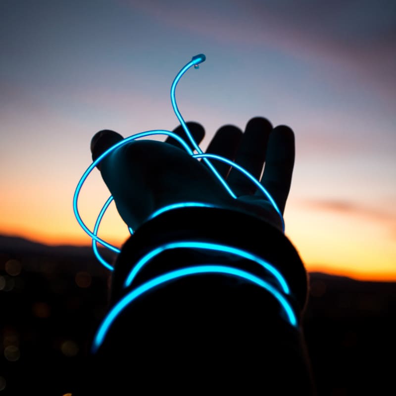 Galsfaserausbau: Blau leuchtendes Kabel um eine Hand gewickelt